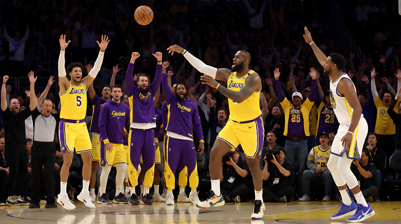 NBA洛杉矶湖人对阵金州勇士比赛现场，詹姆斯完成精彩助攻，队友庆祝得分，球馆内气氛热烈